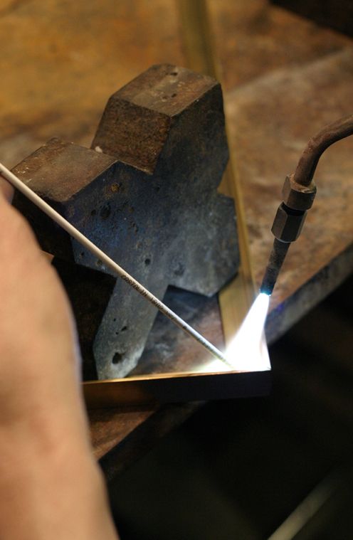 Geste artisanal au chalumeau photographié par Nathalie Barrus dans l'atelier de luminaires d'art Jean Perzel.