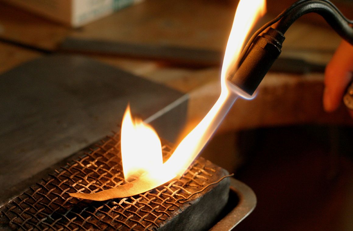 En photo : à la chaleur de la flamme du chalumeau, l'or se plie au désir de l'artisan bijoutier.