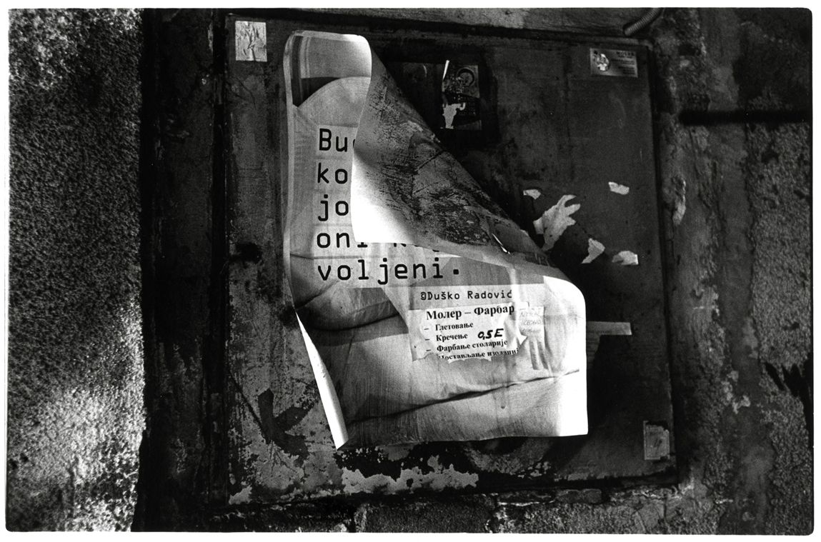 photo en noir et blanc d'une affiche décollée sur un mur à belgrade.