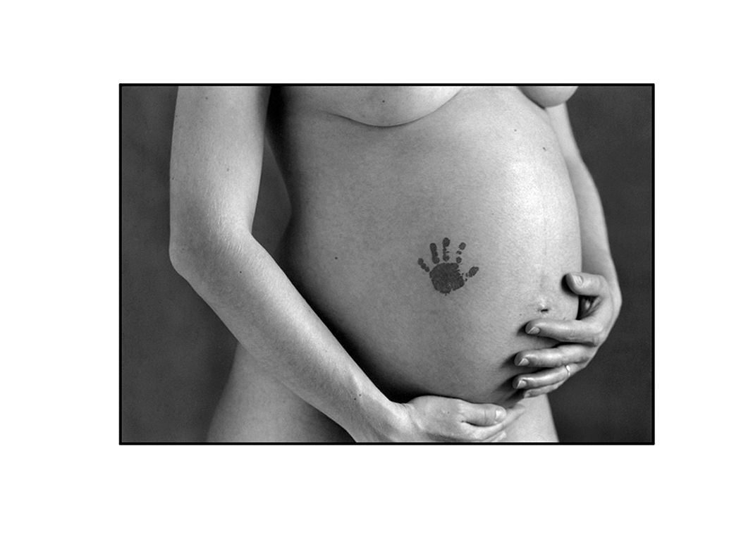 Photo artistique d'un ventre de femme enceinte avec ses mains posées dessus.