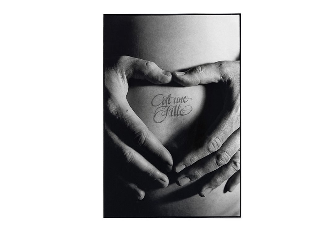 Photo artistique noir et blanc mains en coeur sur ventre de femme enceinte.
