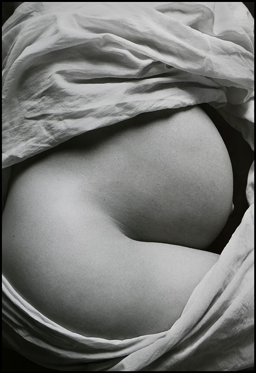 Photographie d'un ventre de femme enceinte entouré d'un drapé.