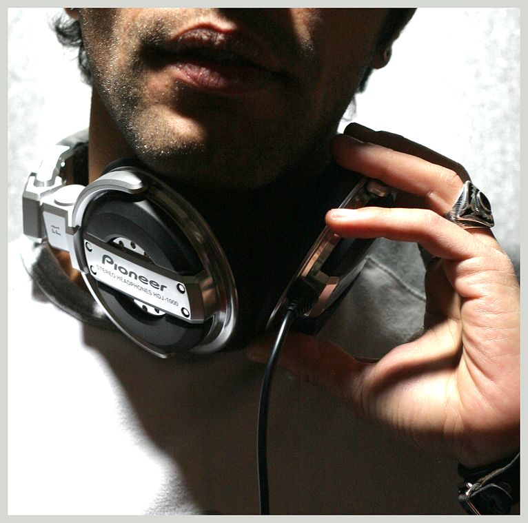 portrait couleur d'une partie du visage d'un dj tenant un casque audio.